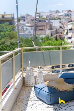 A balcony with a view of a cityscape, a blue cushion, and two white textured vases. - Aegean Blue Hideaway w/ Fireplace, near Acropolis (Athens)