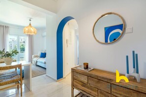 A modern living room with a large window, a dining area with a table and chairs, and a hallway leading to another room. - Aegean Blue Hideaway w/ Fireplace, near Acropolis (Athens)