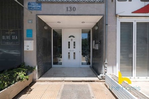 A building entrance with a number 130 sign, a door with glass panels, and a sign for 'OLIVE SEA TRAVEL'. - Aegean Blue Hideaway w/ Fireplace, near Acropolis (Athens)