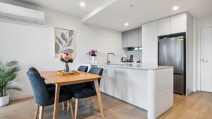 Una cocina moderna con una isla central, armarios blancos y un refrigerador de acero inoxidable.