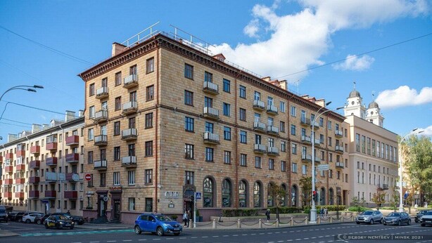 A multi-story building with a classic architectural style, featuring a central entrance with arched windows and a series of balconies on each floor.