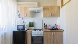 A compact kitchen with a microwave, stove, oven, and a refrigerator.