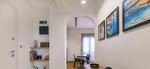A hallway with a dining area, a door with an emergency exit sign, and framed artwork on the wall. - Stylish 2BR Retreat | Walk to Metro & Museums (Athens)
