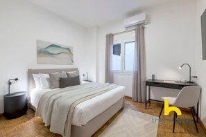 Un dormitorio moderno con cama, mesitas de noche, escritorio y silla.