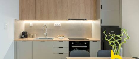 A modern kitchen with a built-in oven, a sink, and a dining area with a table and chairs.