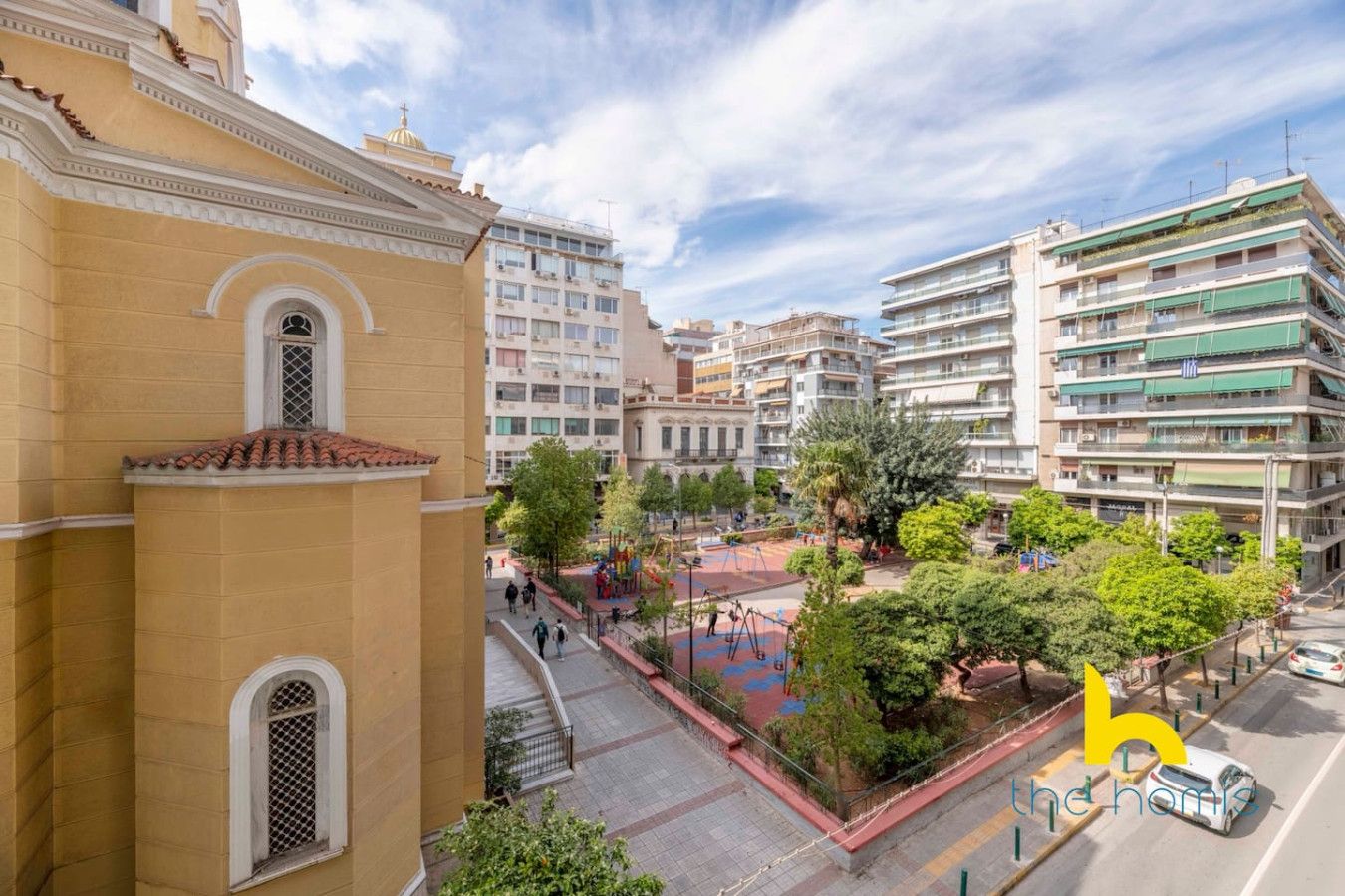 Un quartier résidentiel avec un immeuble jaune, une aire de jeux et des immeubles d’appartements modernes.