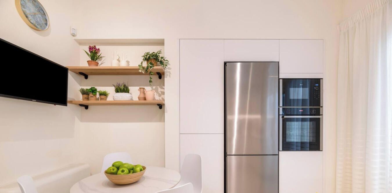 Een moderne keuken met een roestvrijstalen koelkast, een magnetron en een houten plank met planten.