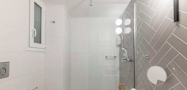 Un bagno con doccia, un water e uno specchio.