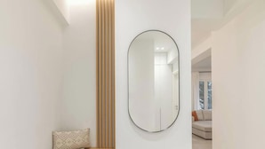 Um interior moderno com um espelho grande, uma almofada estampada e vista para uma sala de estar.