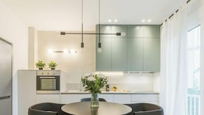 Uma cozinha moderna com área de jantar, com uma ilha central, luminárias pendentes e vista para o exterior.