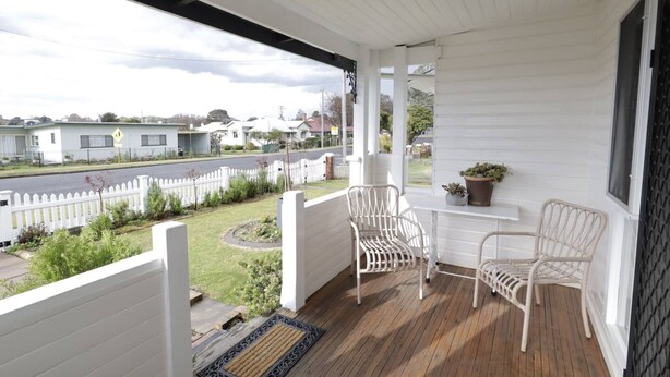 A covered porch with two white wicker chairs, a small table, and a potted plant. - Homely 2-Bed Cottage Near Tenterfield Centre (Tenterfield)