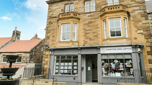 Un immeuble de deux étages abritant une librairie indépendante au rez-de-chaussée, nommée « Chapter One Loftus ».