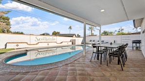 Ett takförsett utomhusområde med en pool, ett matbord med stolar och en vägg där namnet "Scottsdale" står.