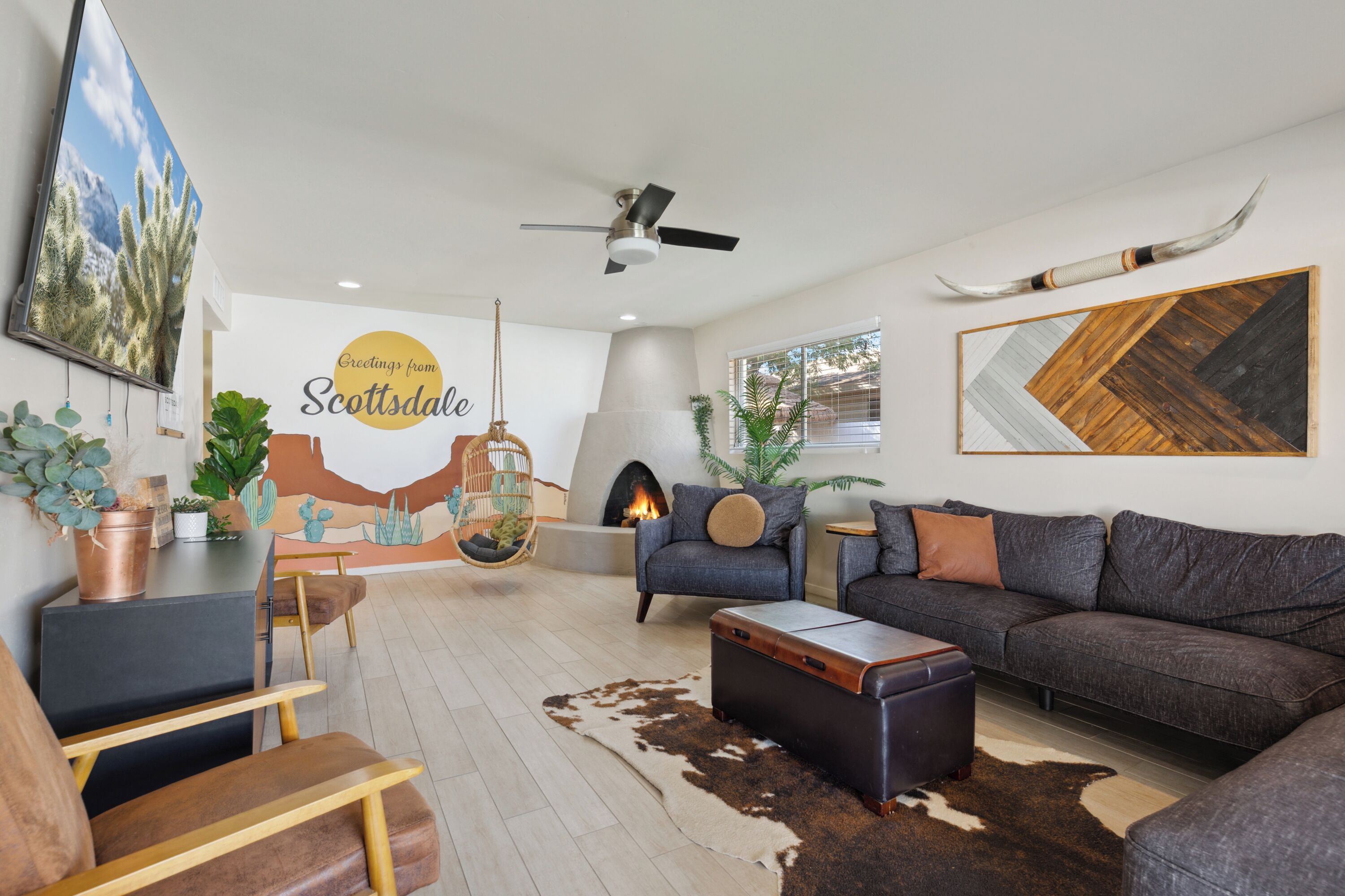 A modern living room with a fireplace, a sofa, a dining area, and a ceiling fan.