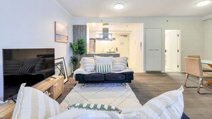 Een moderne woonkamer met een bank, televisie en een eethoek met tafel en stoelen.