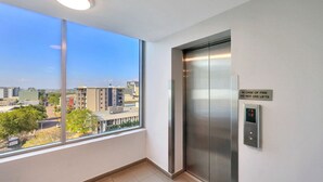 Een moderne lift met een digitaal bedieningspaneel en een bord met de waarschuwing om geen liften te gebruiken bij brand.