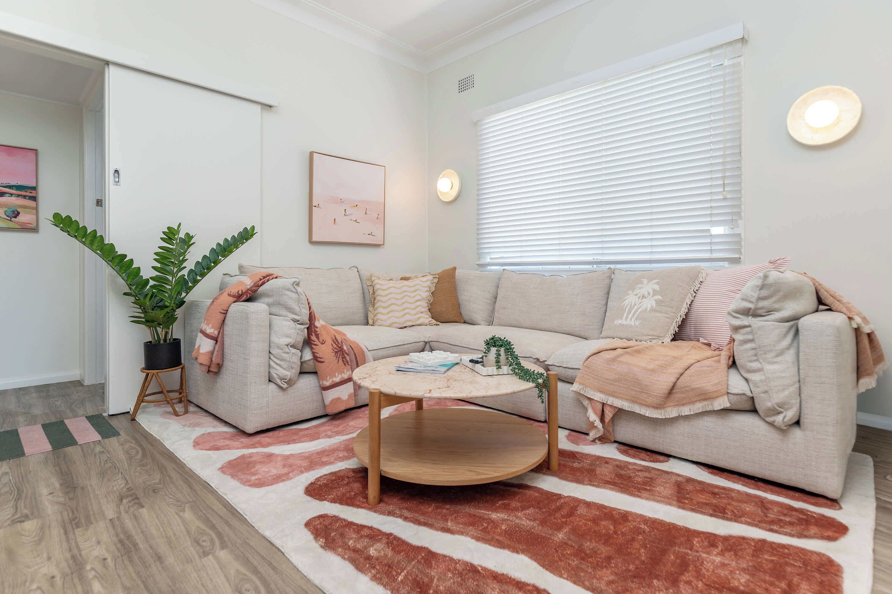 A living room with a sofa, coffee table, and a potted plant.