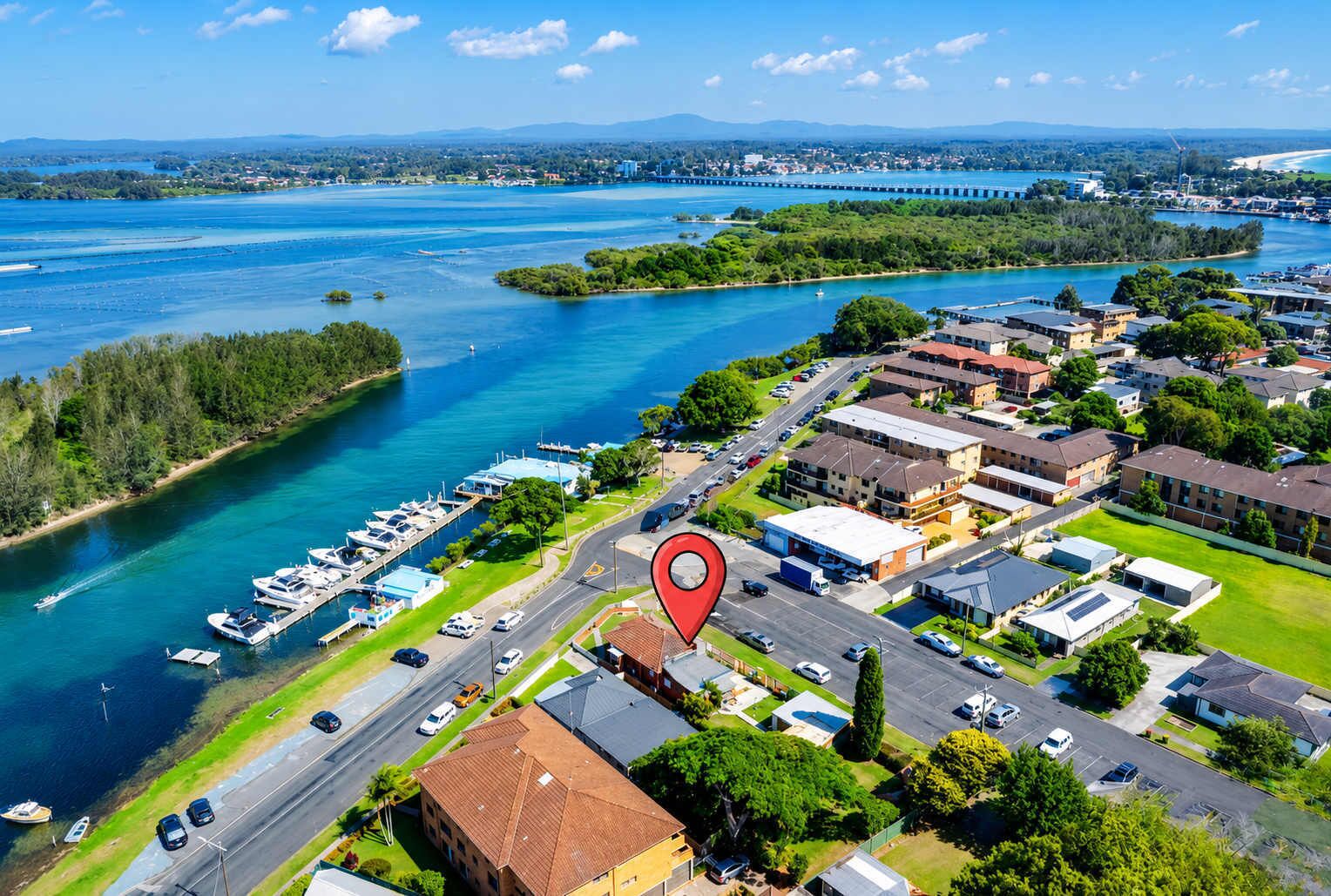 An aerial view of a coastal town with a marina, residential buildings, and a bridge.
