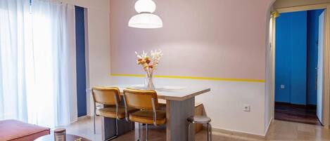 A modern dining area with a table, chairs, and a hanging light fixture.