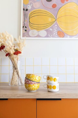 A kitchen counter with a vase of dried flowers, a patterned bowl, and a polka-dotted mug. - Vibrant Retreat Funky Style & Acropolis View! (Athina)