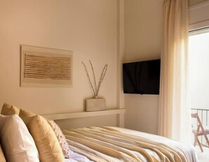 A bedroom with a bed, a mounted TV, a window with curtains, and a wall-mounted shelf with a decorative item. - Luxurious Zen Retreat W/Balcony & 300mbps WiFi (Athina)