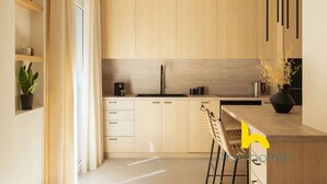A modern kitchen with light wood cabinets, a black faucet, and a wooden countertop. - Luxurious Zen Retreat W/Balcony & 300mbps WiFi (Athina)