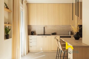A modern kitchen with light wood cabinets, a black faucet, and a wooden countertop. - Luxurious Zen Retreat W/Balcony & 300mbps WiFi (Athina)