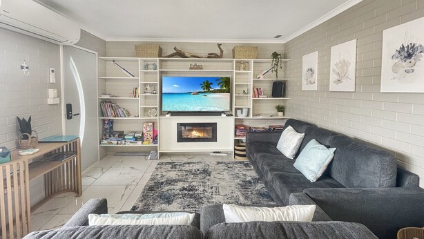 Ein modernes Wohnzimmer mit Flachbildfernseher, Kamin und grauem Sofa.