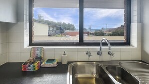 Eine Küche mit Fenster, Spüle und einer Arbeitsfläche mit Tee und einem Geschirrtuch.
