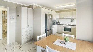 Eine moderne Küche mit weißen Schränken, einem Edelstahlkühlschrank und einem Holzessttisch.