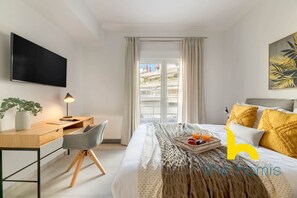Une chambre d’hôtel moderne équipée d’un lit, d’un bureau, d’une chaise, d’une télévision et d’une fenêtre avec des rideaux.