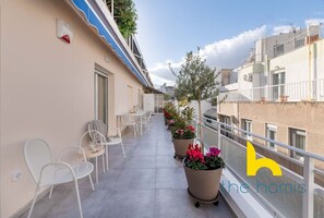 A balcony with outdoor seating, potted plants, and a railing. - Upscale central APT, Patio near Hospitals & Metro (Μενεμένη)