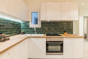Eine moderne Küche mit weißen Schränken, einer grünen Fliesenrückwand, einem Einbauofen und einem Fenster über der Spüle.