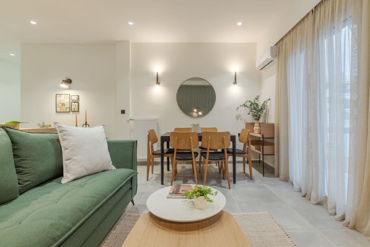 A modern living room with a green sofa, a round dining table with chairs, and a coffee table.
