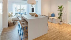 Cozinha moderna com ilha central, banquetas e vista para a cidade através de amplas janelas.