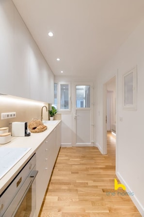 Une cuisine moderne avec des armoires blanches, un plan de travail en bois et un four encastré.