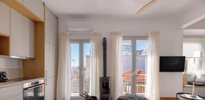 A modern kitchen with a built-in oven, a stove, and a flat-screen TV mounted on the wall. - Acropolis Hillside Escape Fireplace & Sea Views (Athina)