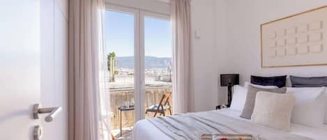 Ett hotellrum med en säng, utsikt genom ett stort fönster, en stol och ett bord.