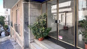 Un edificio con un tendaggio blu, un vaso con una pianta davanti e un cartello sulla porta.