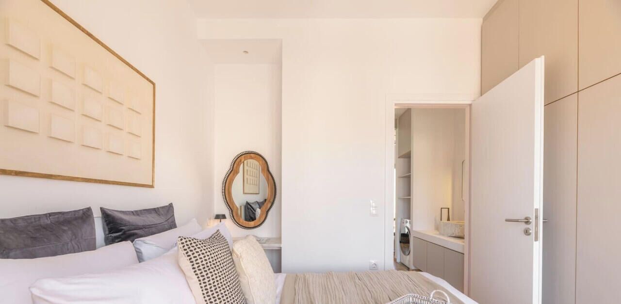 A bedroom with a bed, a mirror, a wardrobe, and a door leading to a bathroom.