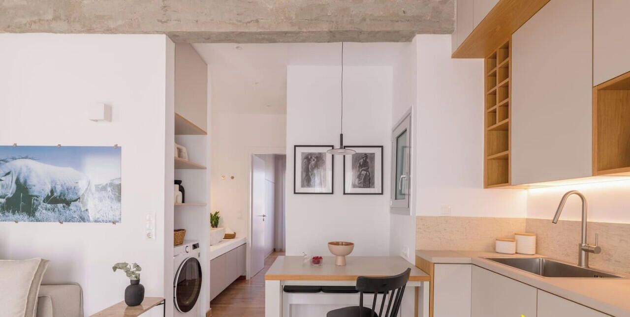 A compact kitchen with a washing machine, a dining area, and a sink.