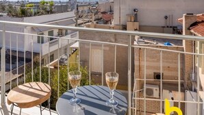 Una terrazza sul tetto con due tavoli rotondi e due sedie, con vista sulla città.