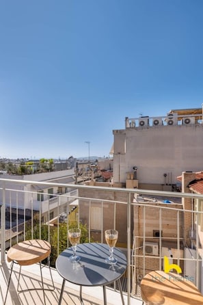A rooftop terrace with two round tables and two chairs, overlooking a cityscape. - Acropolis Hillside Escape Fireplace & Sea Views (Athina)