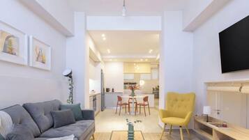 Una sala de estar moderna con un sofá, un sillón amarillo y un comedor con mesa y sillas.