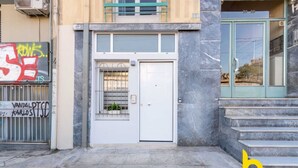 A building entrance with a white door, a metal gate with graffiti, and a staircase leading up to a balcony. - Cozy Hub - Work, Relax, Explore - Prime Location (Athina)