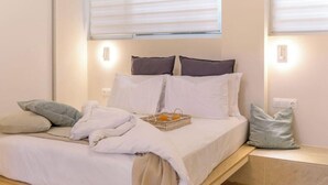 A neatly made bed with white linens, a basket of oranges, and a few pillows. - Cozy Hub - Work, Relax, Explore - Prime Location (Athina)