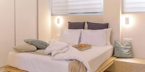 A neatly made bed with white linens, a basket of oranges, and a few pillows. - Cozy Hub - Work, Relax, Explore - Prime Location (Athina)