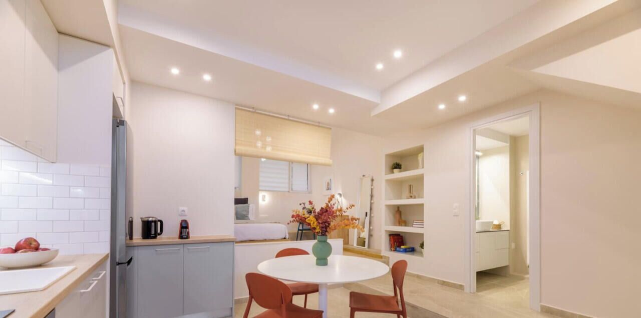 Una cocina moderna con armarios blancos, una mesa redonda y un jarrón con flores.