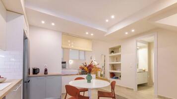 Una cocina moderna con armarios blancos, una mesa redonda y un jarrón con flores.