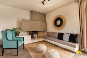 Ein modernes Wohnzimmer mit Sofa, einem Türkis-Armlehnstuhl, Kamin und Wanddeko.